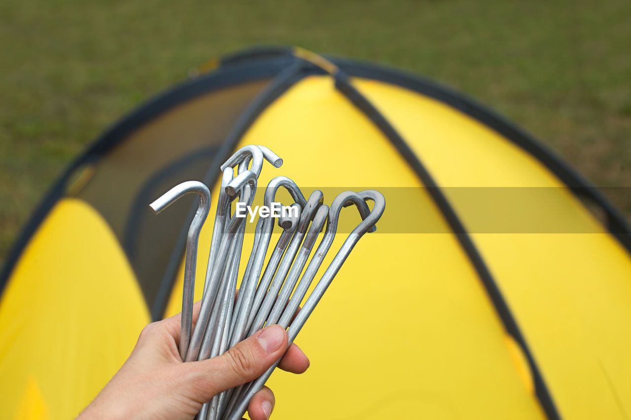 Aluminum stakes for the installation of a tourist yellow tent in the hand close-up. lightweight 