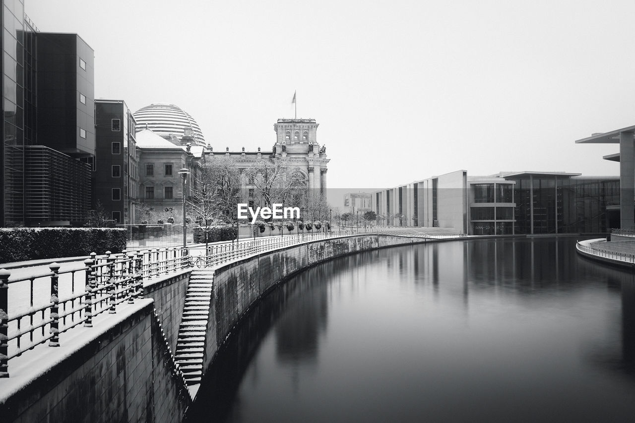 Reichstag building by river against clear sky