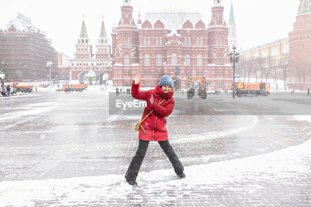 FULL LENGTH OF WOMAN STANDING ON SNOW COVERED CITY