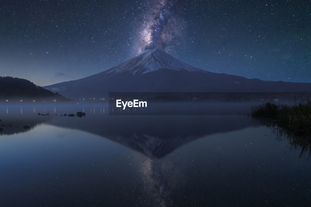 Scenic view of lake and mountains against sky at night