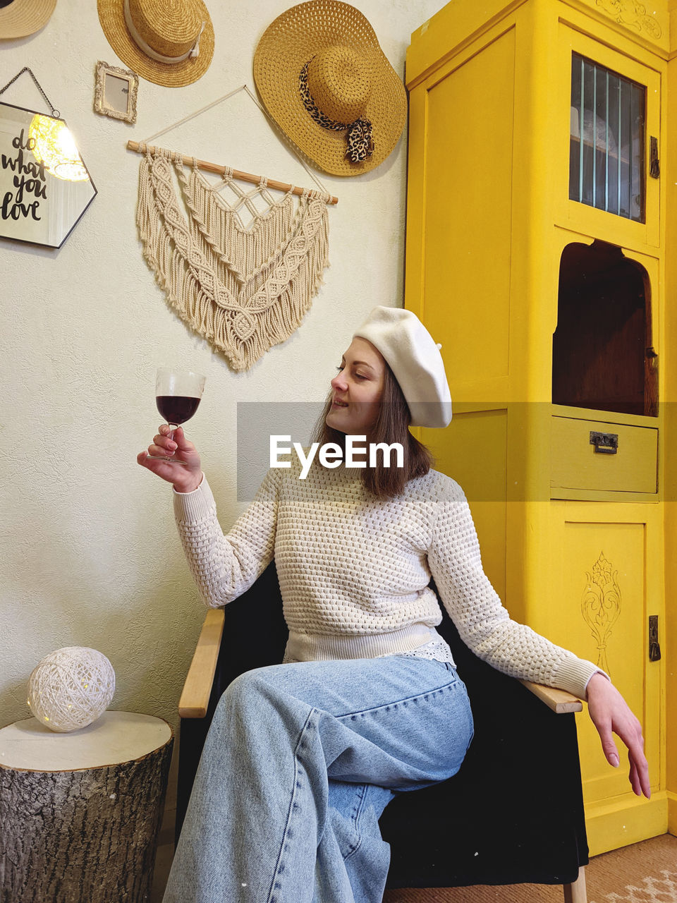 Young woman in beret sits in cozy home, room with music record in hands. vintage yellow cabinet.