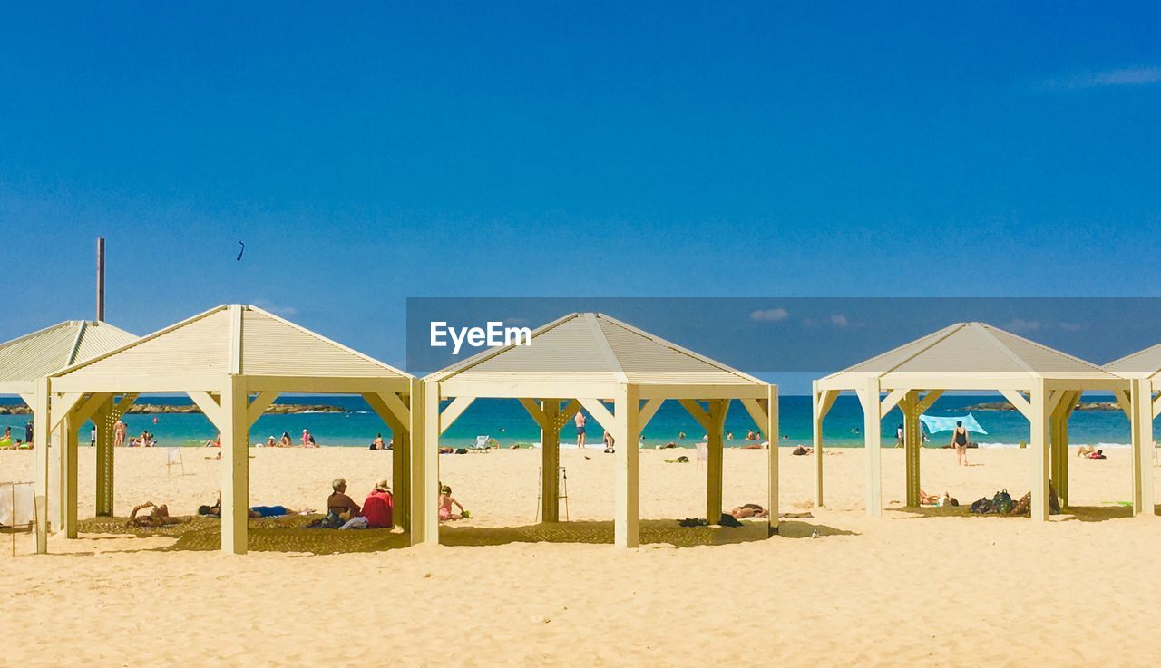 LOUNGE CHAIRS ON BEACH AGAINST CLEAR BLUE SKY