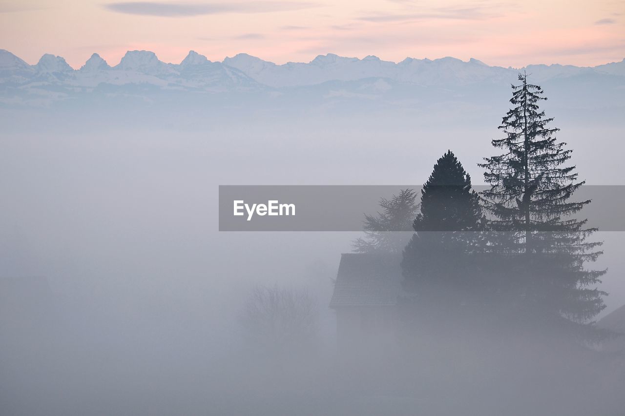 Scenic view of sea in front of mountains in foggy weather