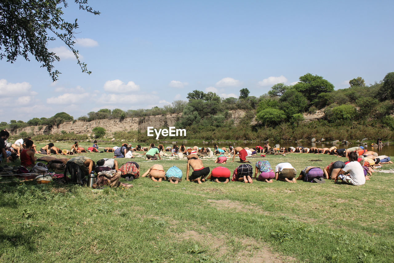 People kneeling and bending on grassy field during religious ceremony