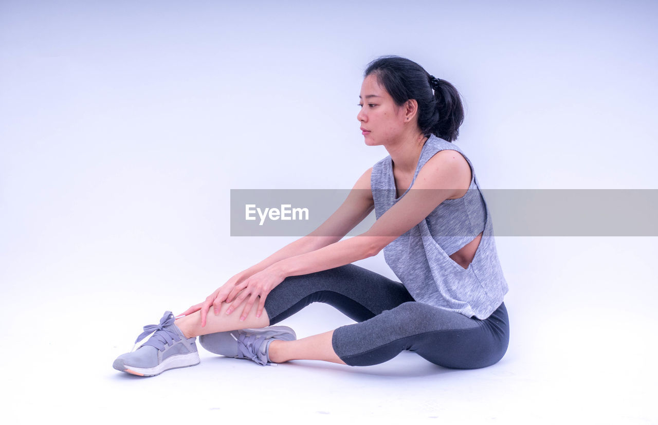 Young woman stretching against white background