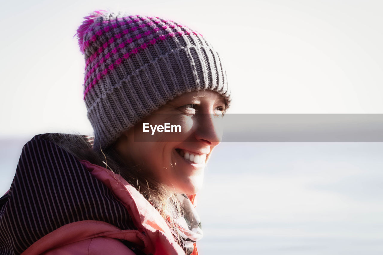 Smiling woman looking away while standing outdoors during winter