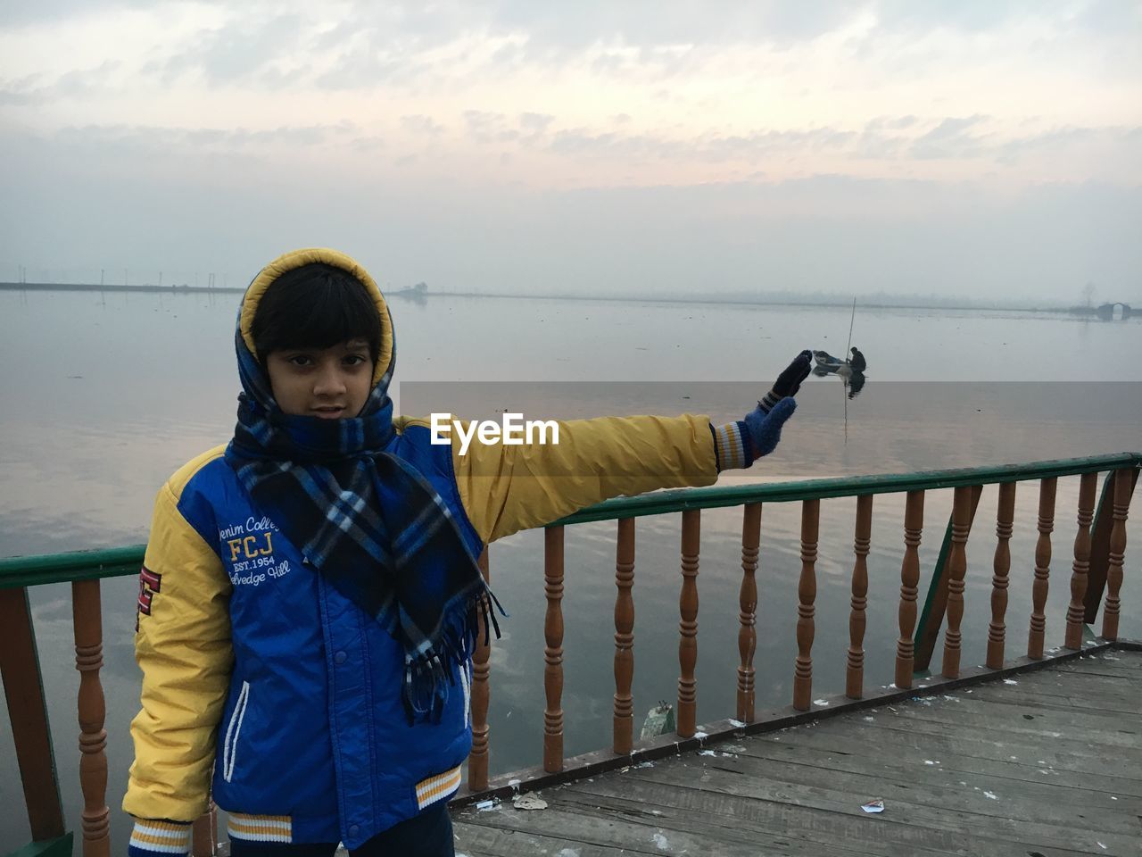 FULL LENGTH OF BOY STANDING IN SEA AGAINST SKY DURING SUNSET