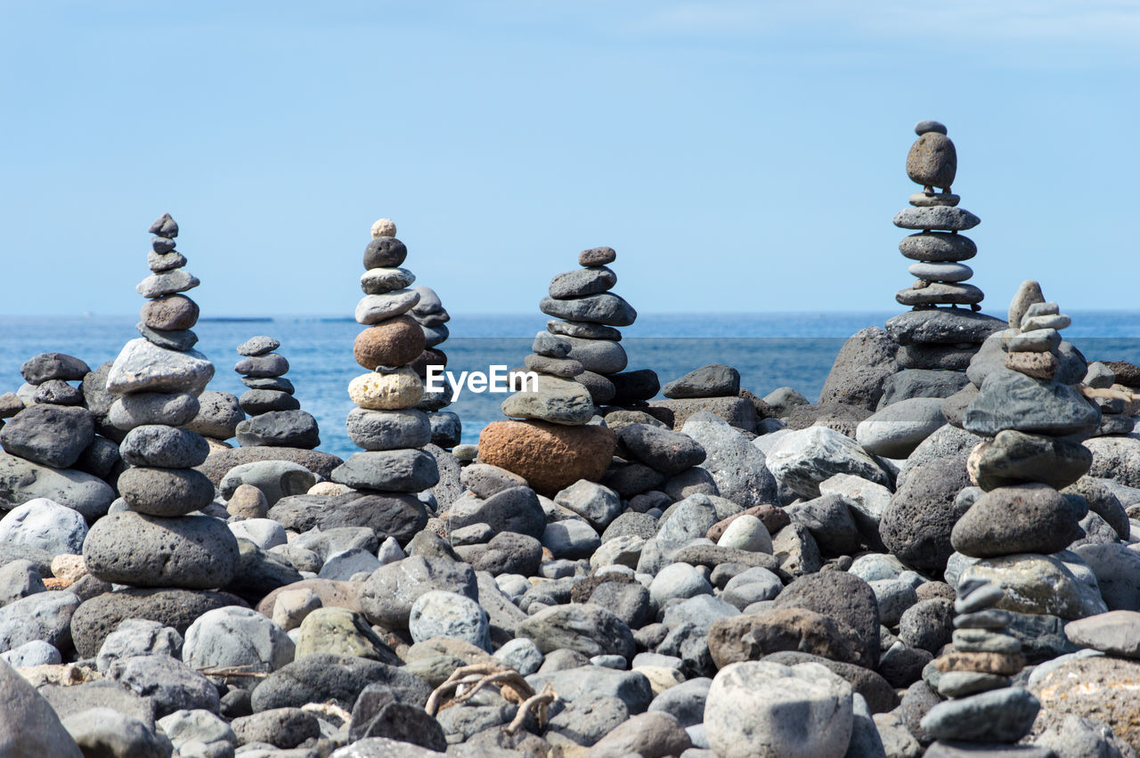 Stack of stones on rocky shore at sea