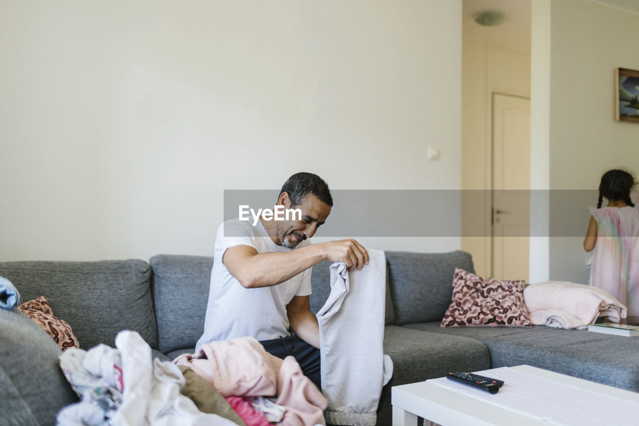 Man folding clothes on sofa