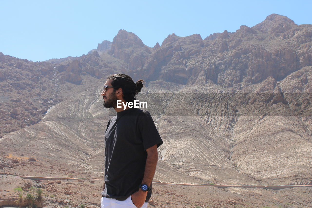 Young man standing against mountain range