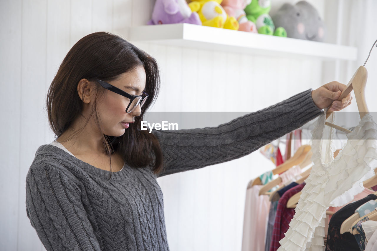 Beautiful fashion designer holding garment standing in clothing design studio