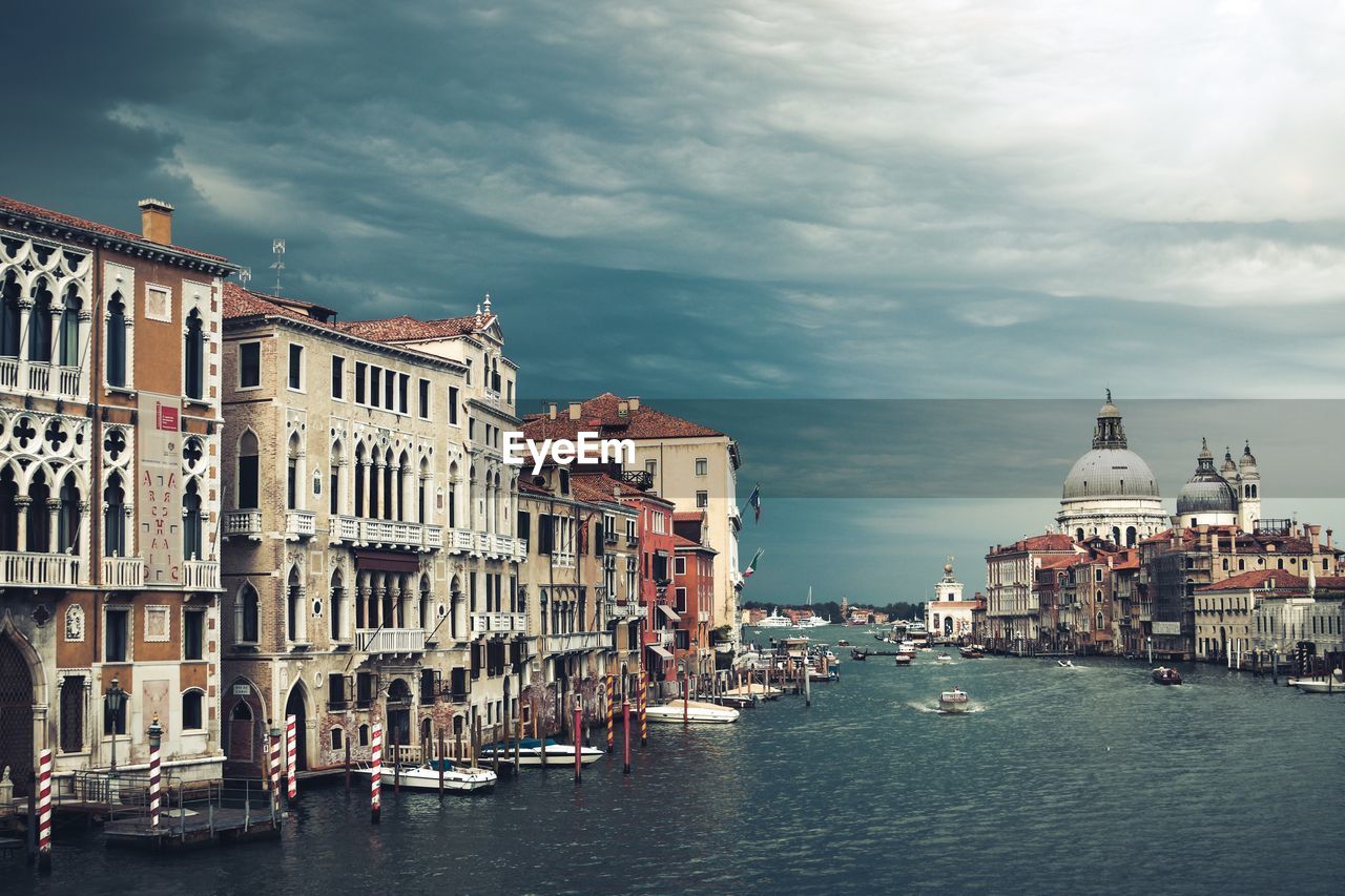 View of canal with church against cloudy sky