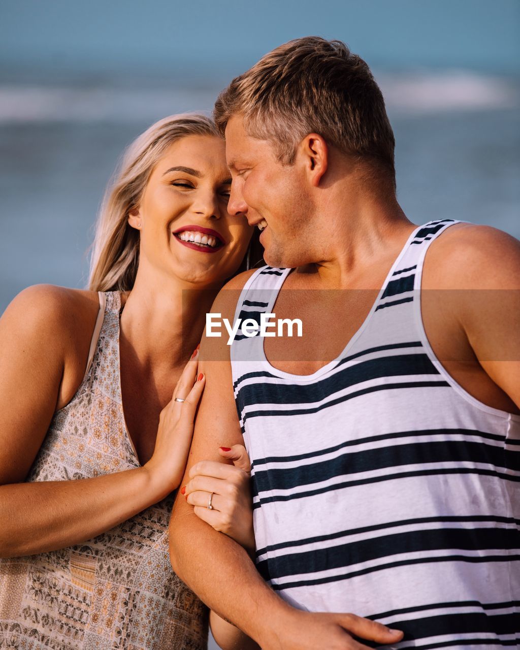 YOUNG COUPLE KISSING IN WATER AT SHORE