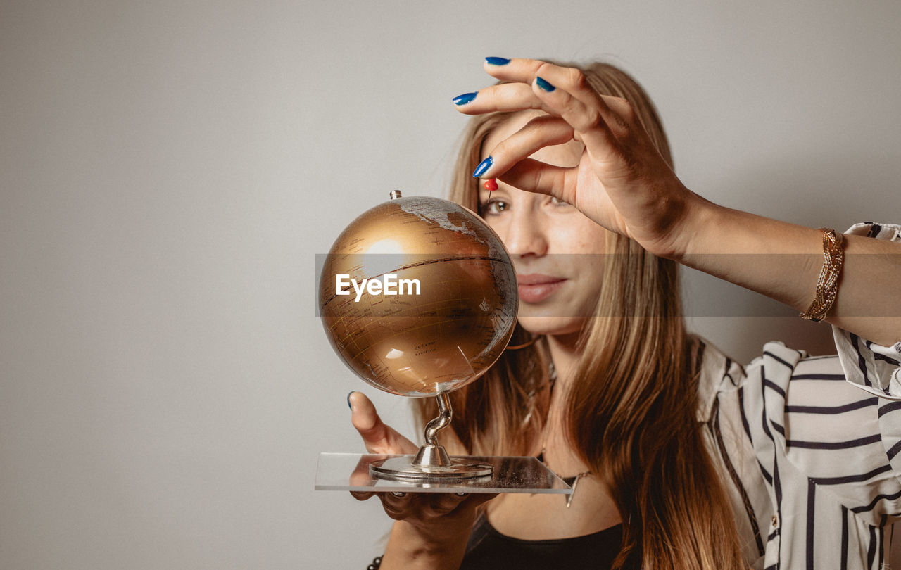 Woman looking at globe against gray background