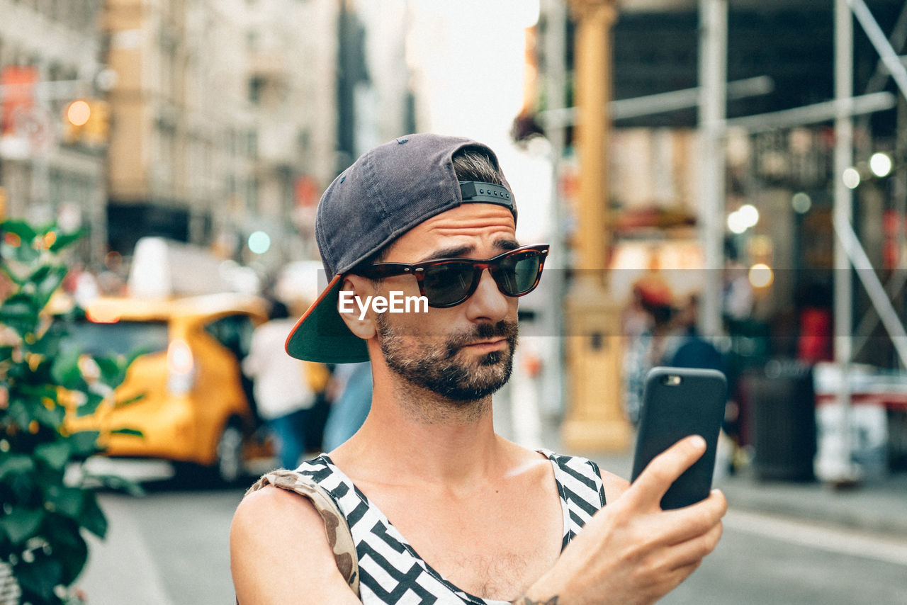 Man taking selfie through smart phone in city