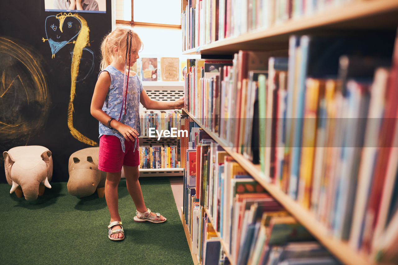 Schoolgirl looking for books in school library. elementary education. back to school