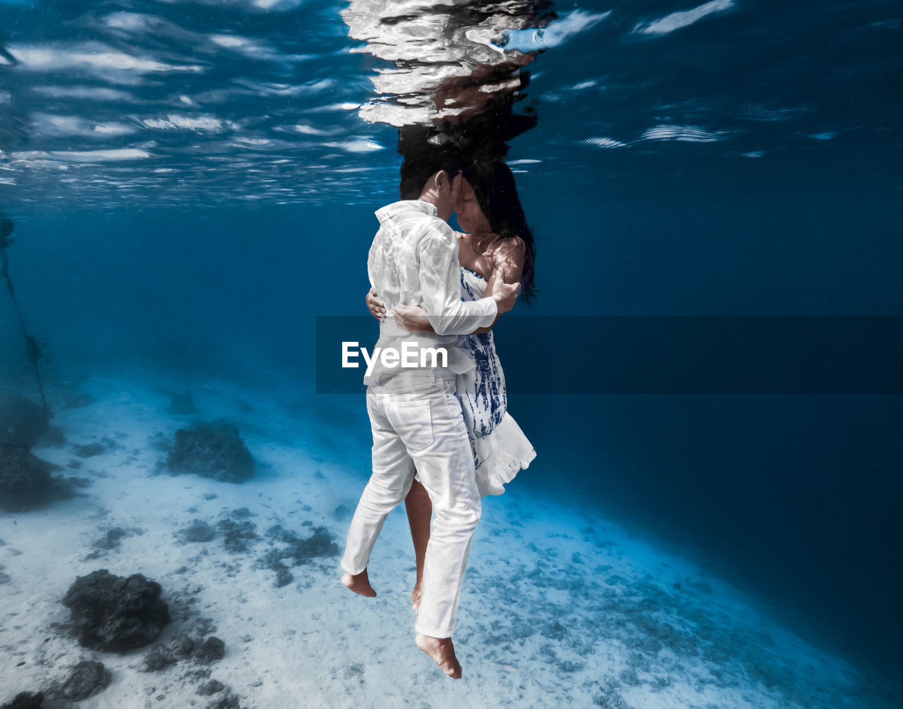 REAR VIEW OF WOMAN SWIMMING IN SEA