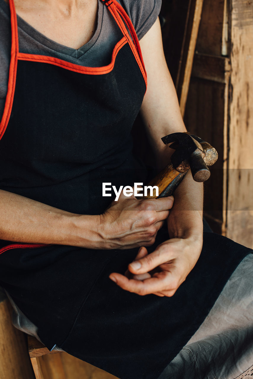 Hands of female carpenter holding hammer and mallet, close up