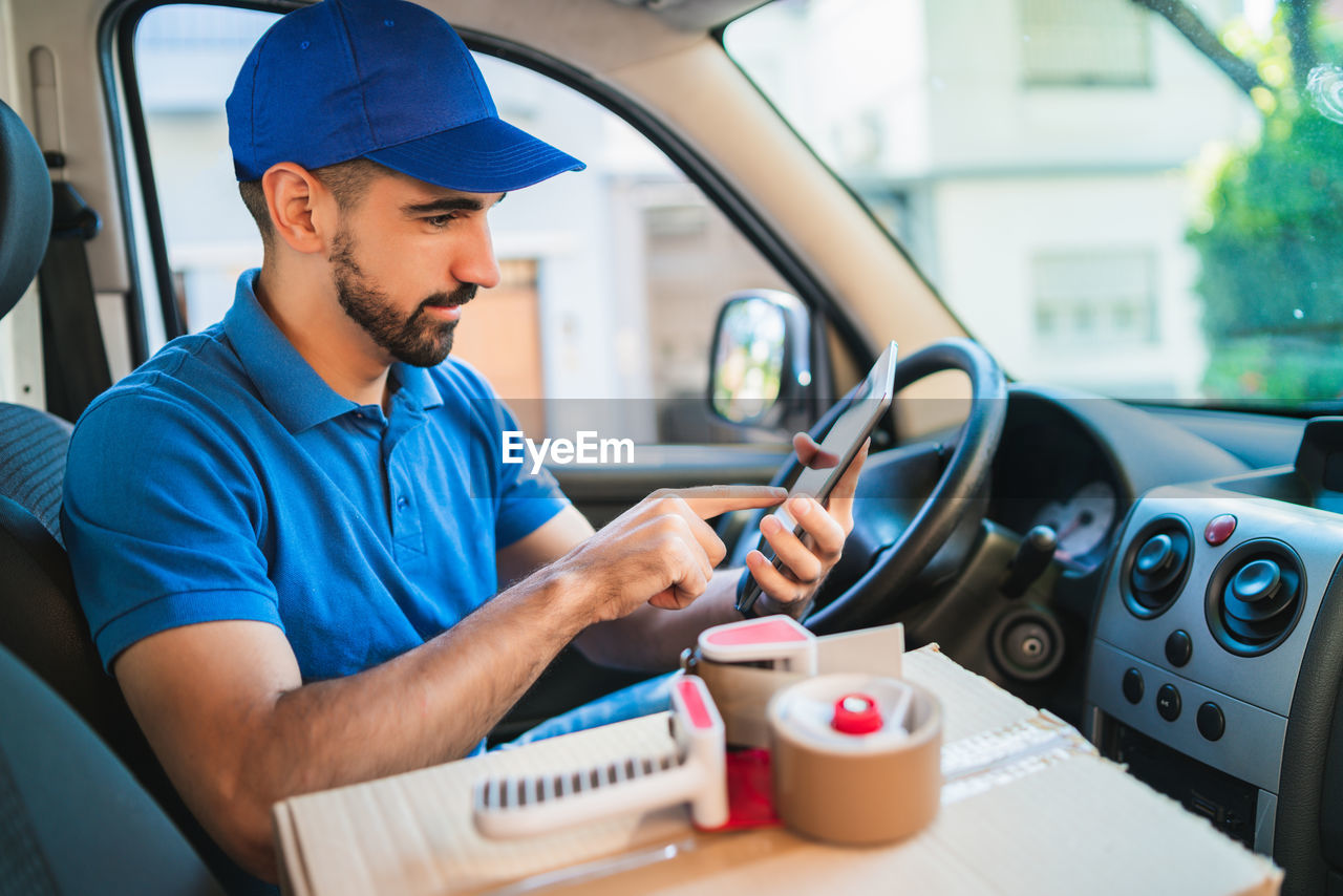 MAN USING MOBILE PHONE WHILE SITTING IN BUS