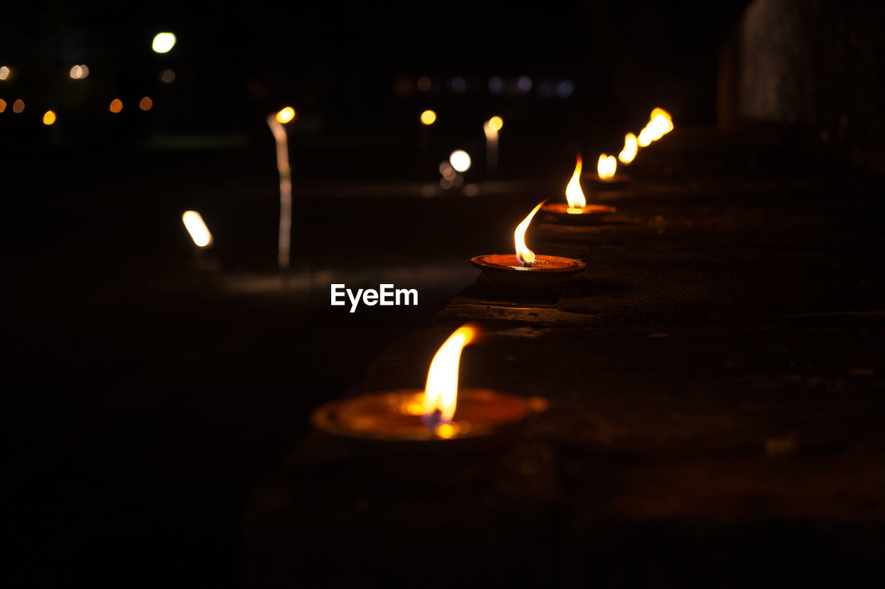 Close-up of lit diyas at night