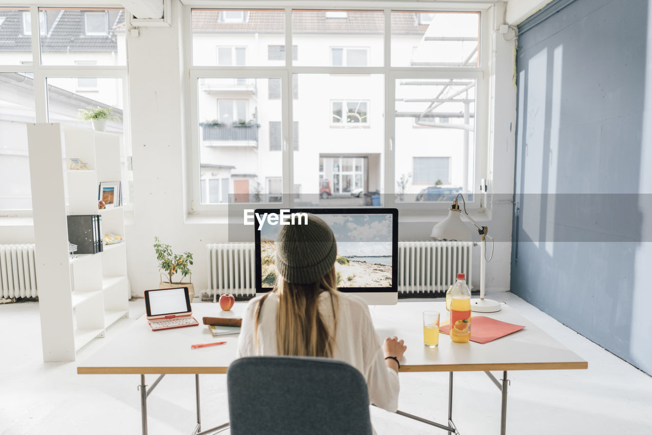 Back view of freelancer working at desk in a loft