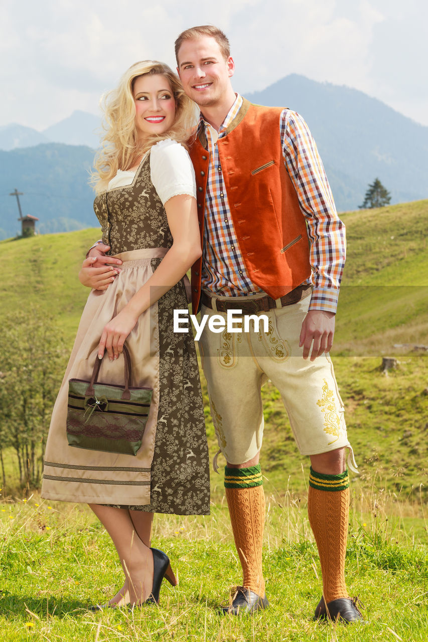 Portrait of young man with girlfriend standing on grassy field