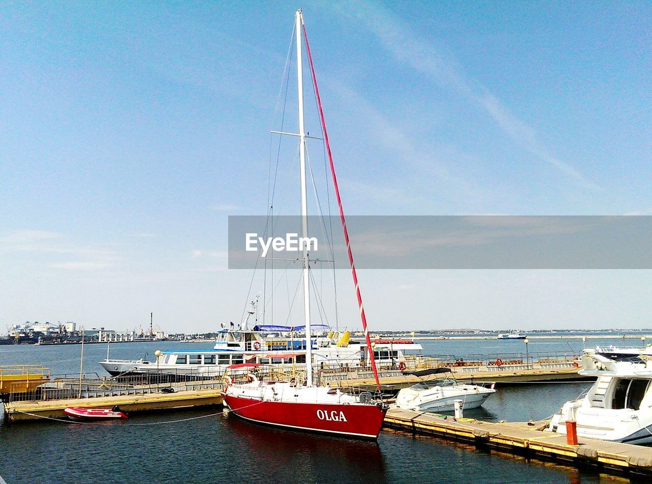 BOATS MOORED IN HARBOR AGAINST SKY