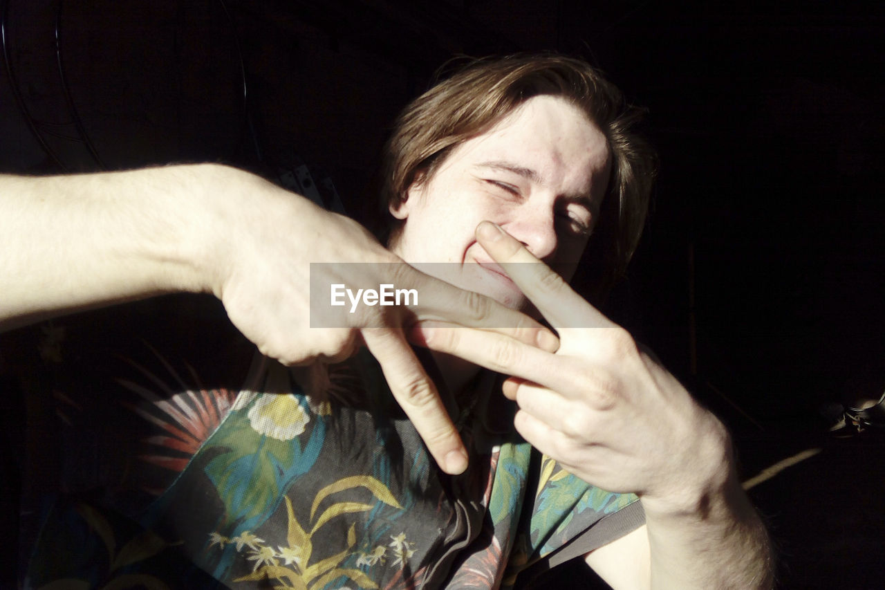 Young man gesturing peace sign at home