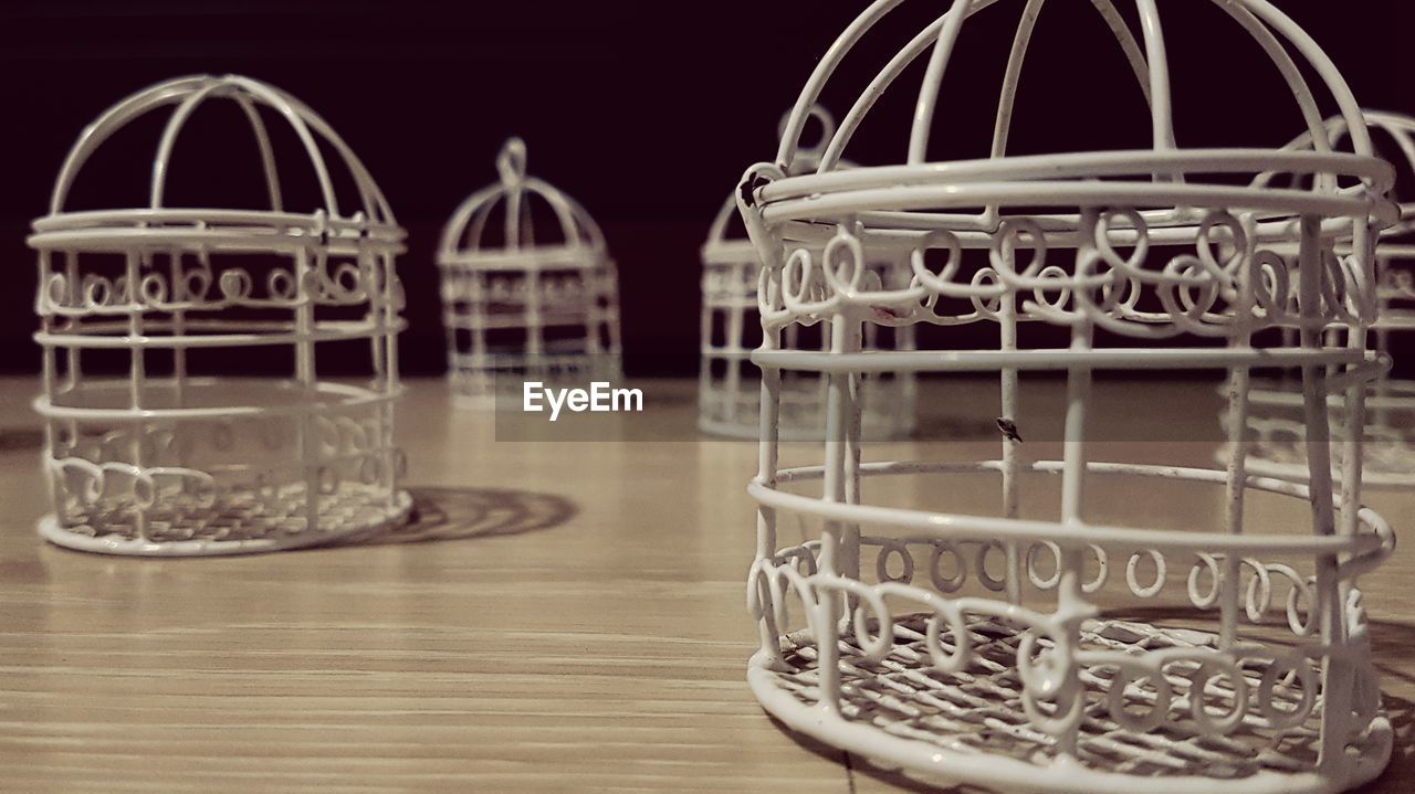 Close-up of empty birdcages on table against black background