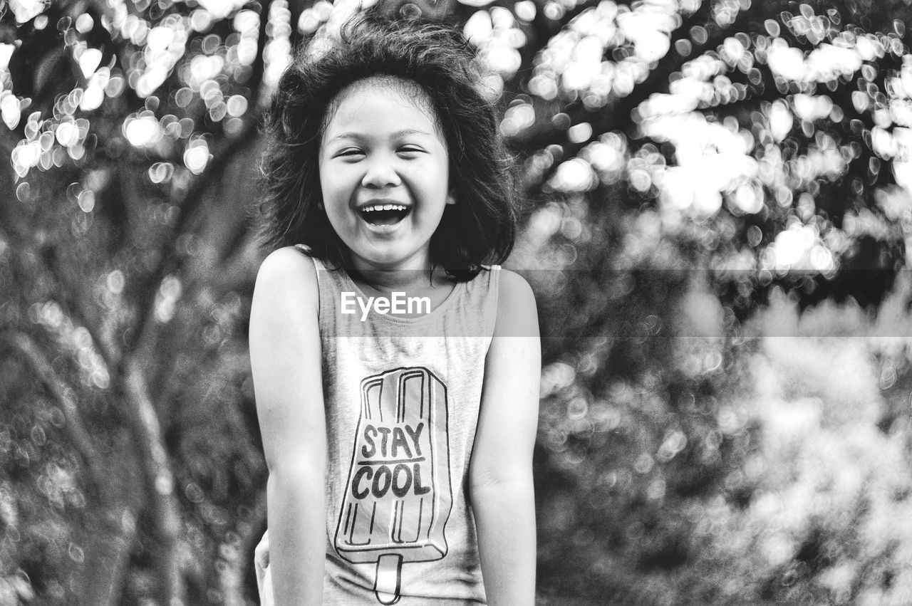 Close-up portrait of smiling girl against trees