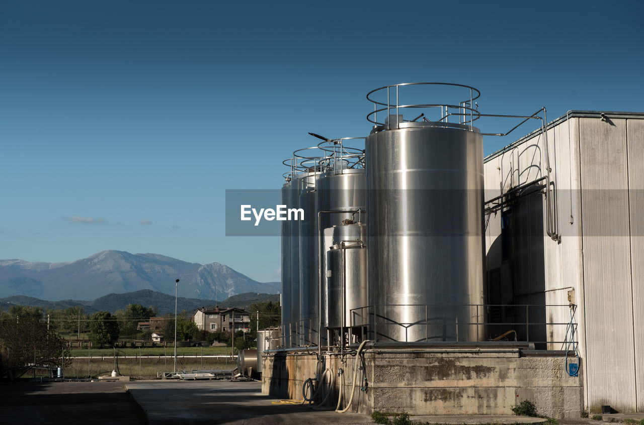 Metallic silos at industry against clear blue sky