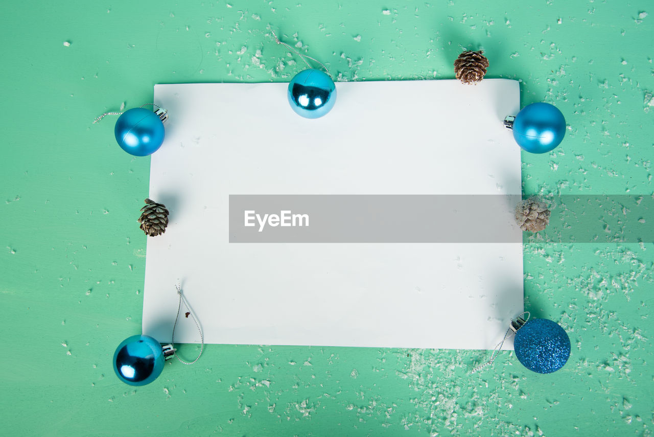 Directly above shot of blank paper with christmas decorations over green background