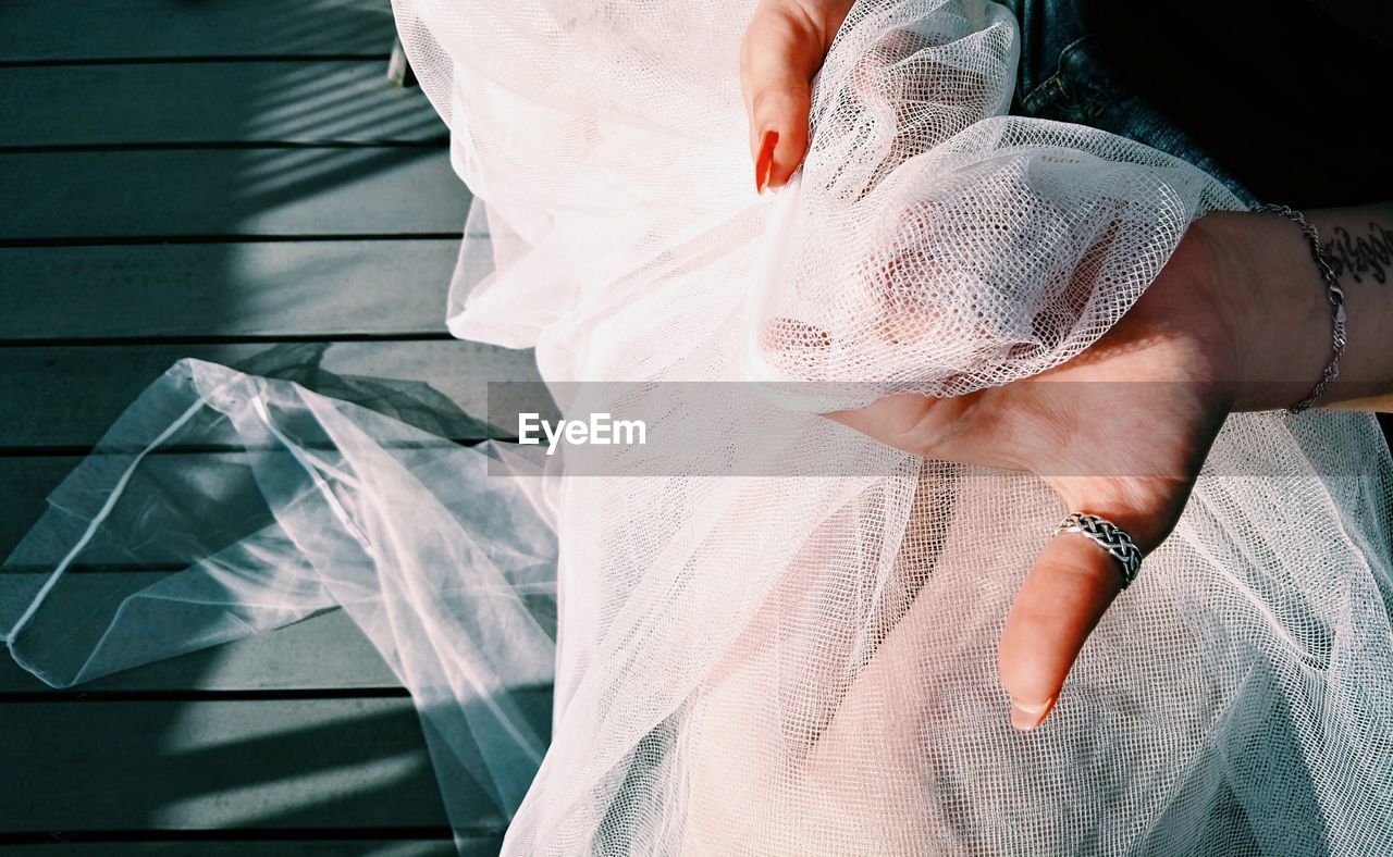 Cropped hands of bride holding white veil