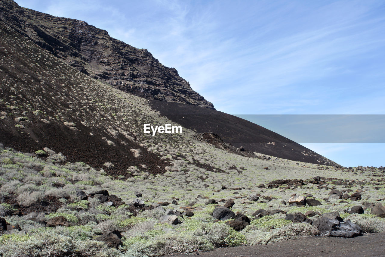 LOW ANGLE VIEW OF ROCKS ON MOUNTAIN AGAINST SKY