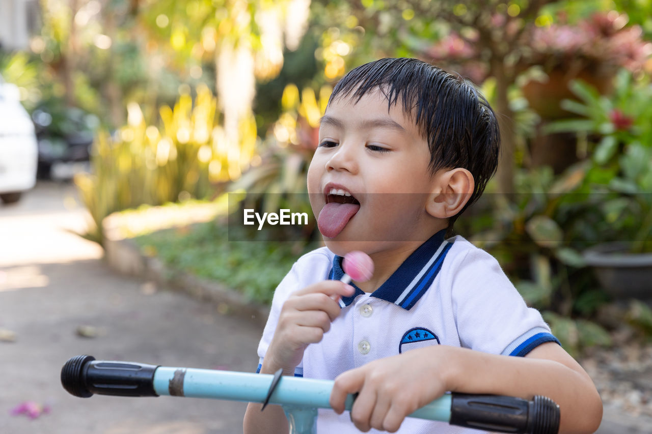 Cute boy eating lollipop while on footpath