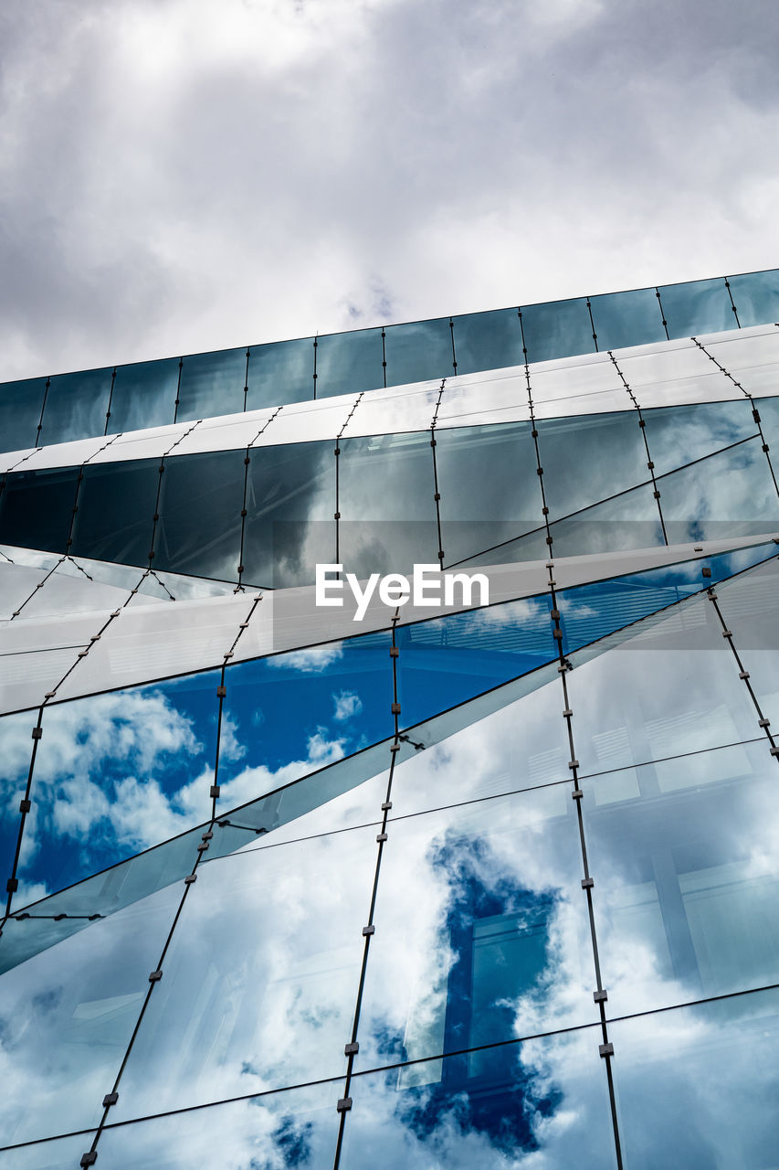 Glass building with reflection against cloudy sky