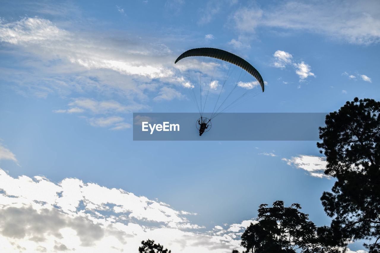 Low angle view of person paragliding against sky