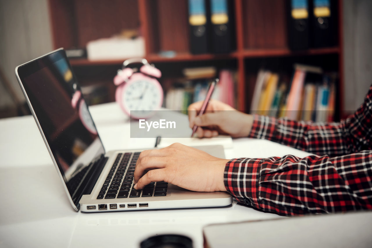 YOUNG WOMAN USING LAPTOP ON TABLE