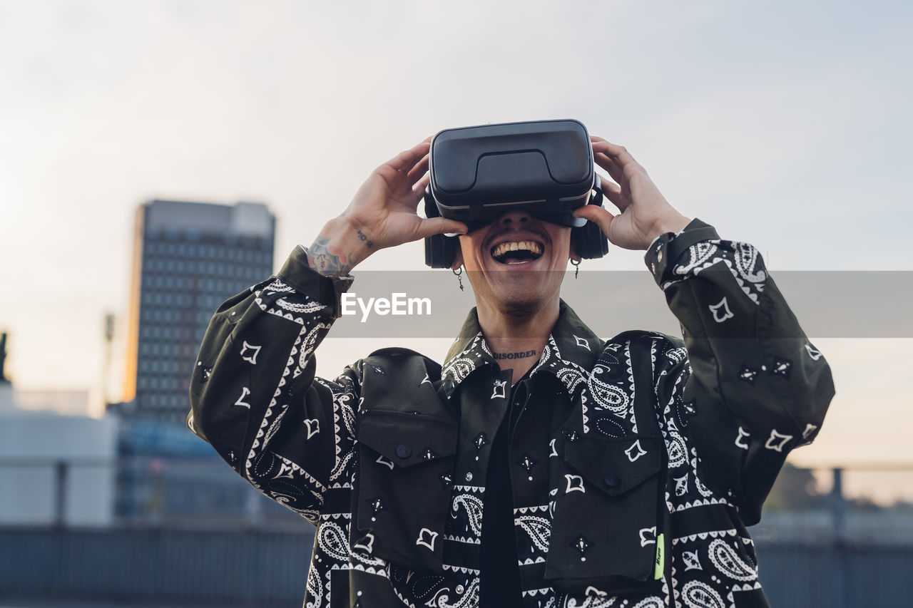 Happy man enjoying wearing virtual reality headset in city