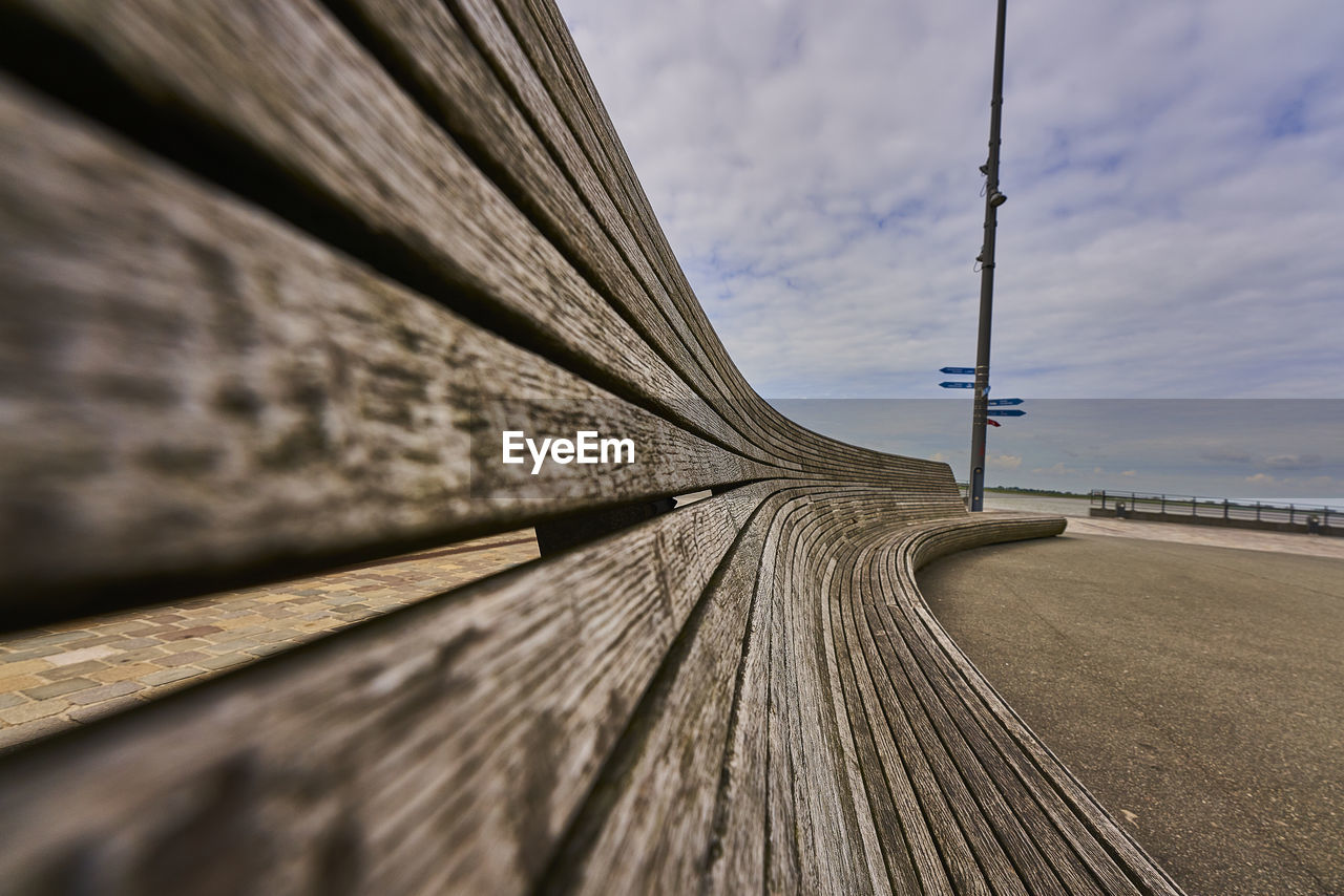 Close-up of wooden bench structure against sky