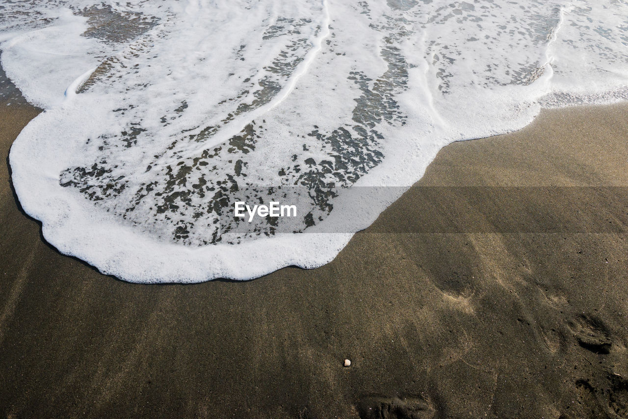 Beautiful soft wave on black sand at the sea, sunny day.