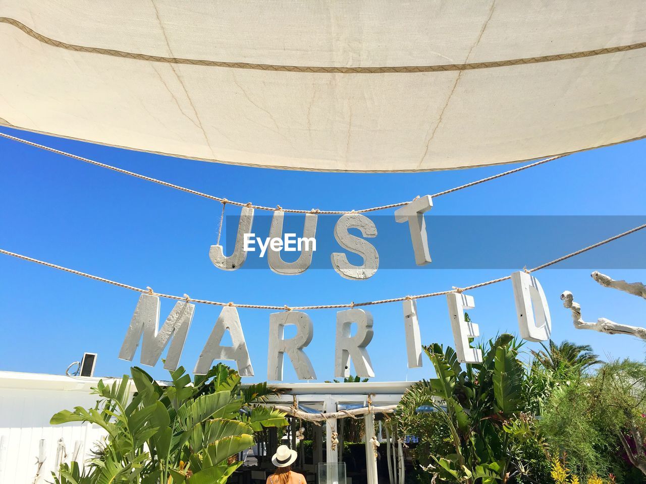 Low angle view of just married text hanging on ropes against clear sky