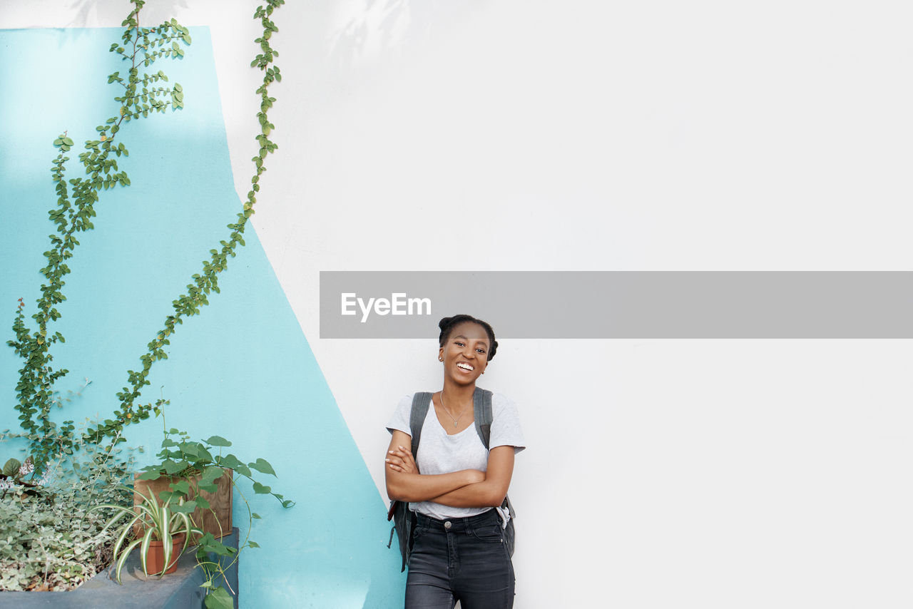 Portrait of young woman standing against wall