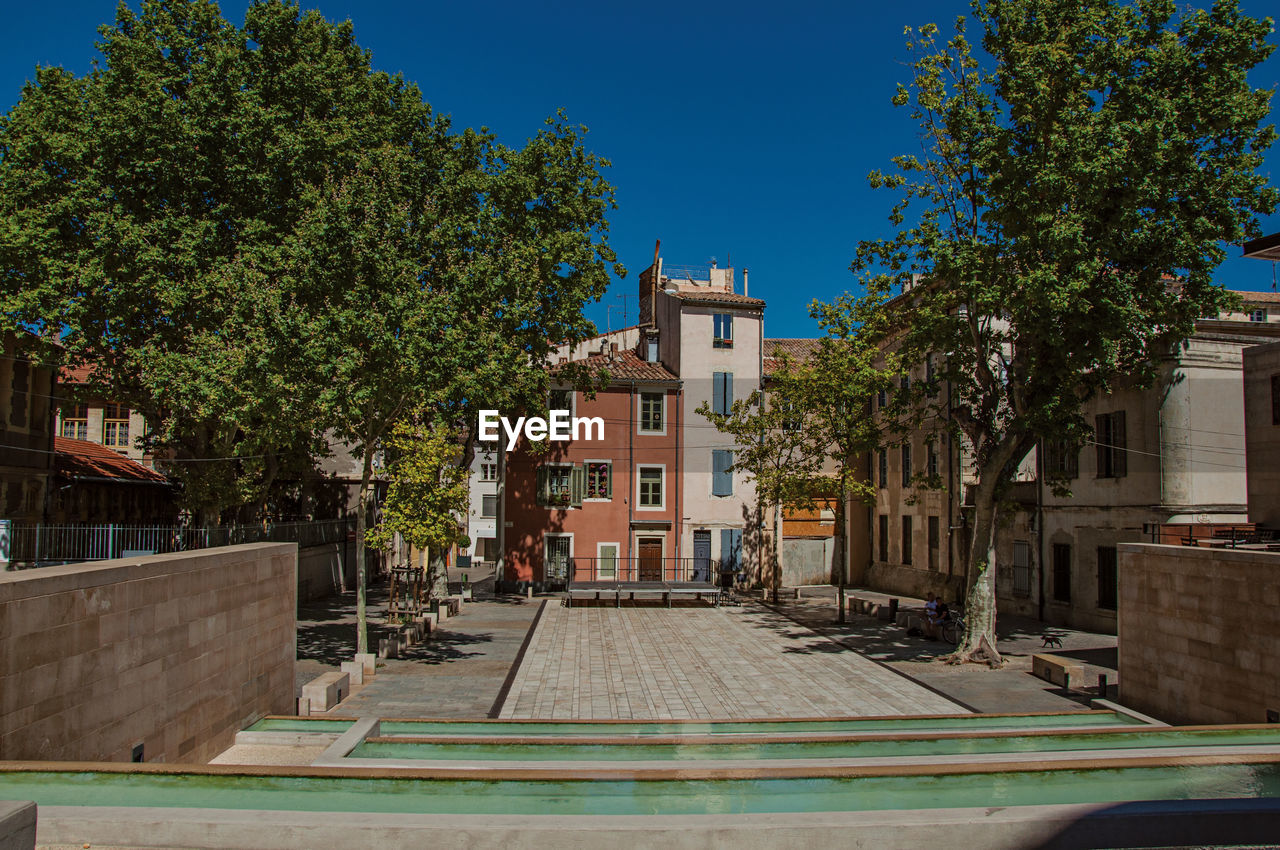 Quiet square with trees and buildings at the city center of nimes, in the french provence.