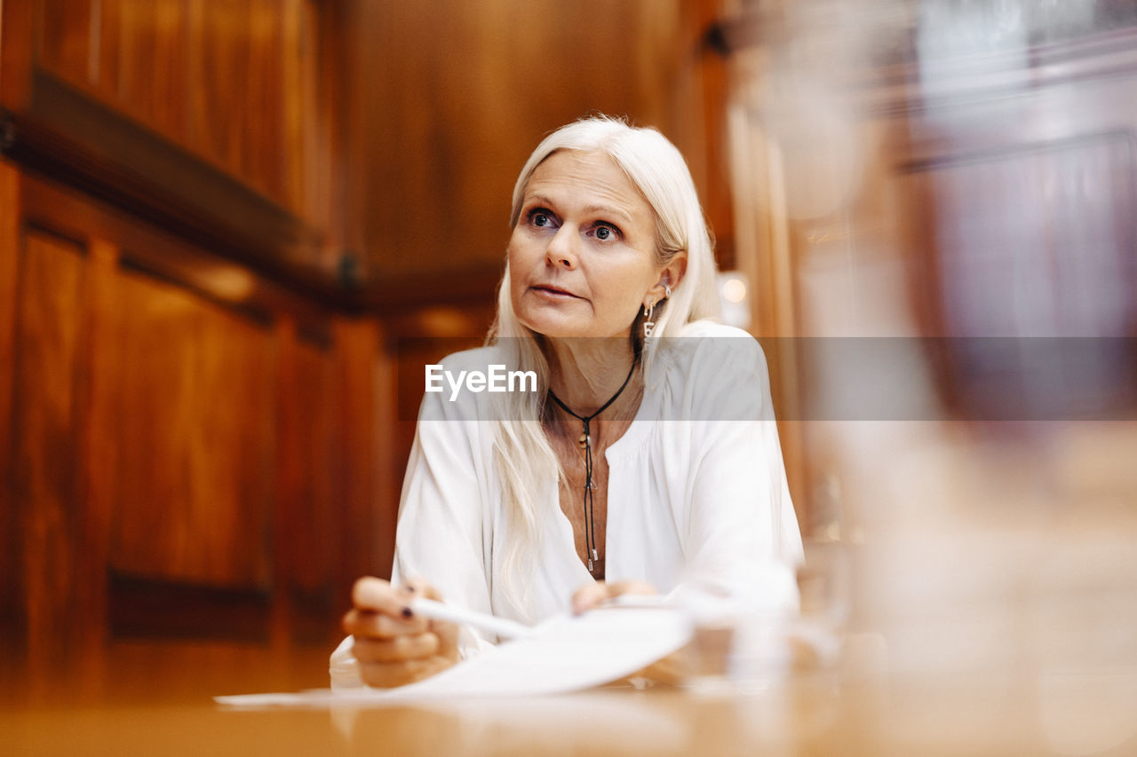 Confident businesswoman sitting with contract document in board room