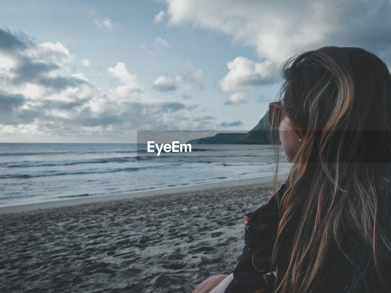 Side view of mid adult woman standing at beach against sky