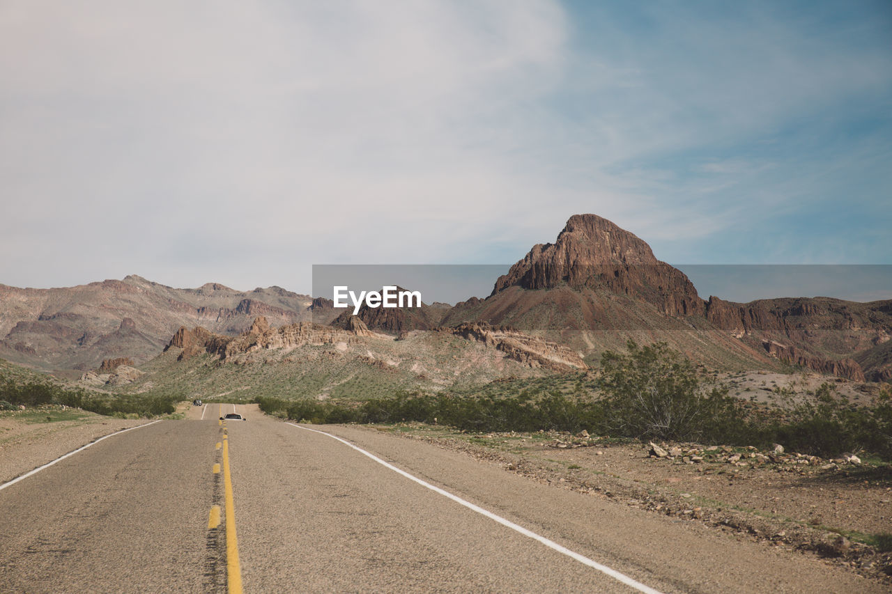 Empty road by mountain against sky