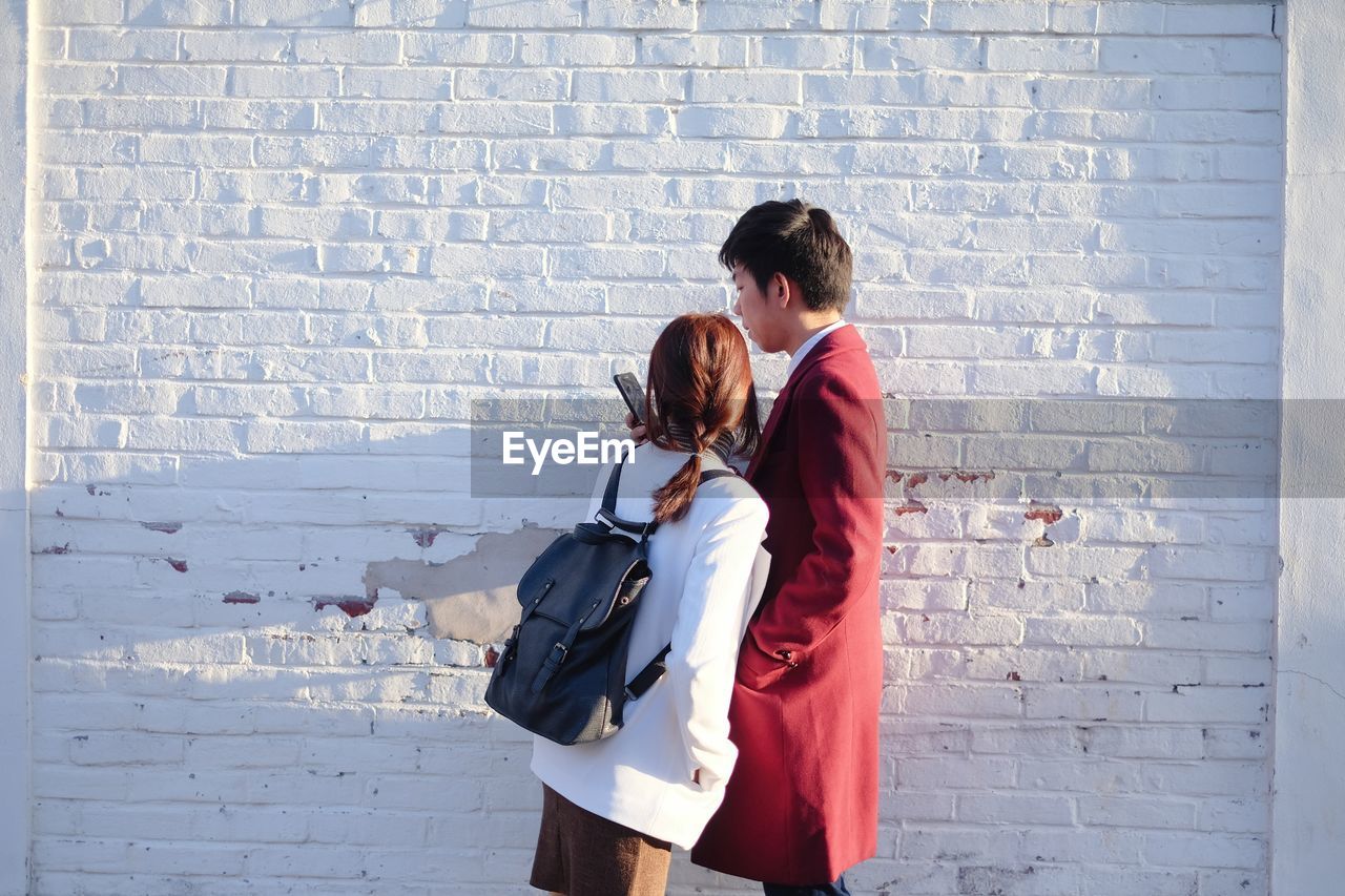 Couple standing against brick wall