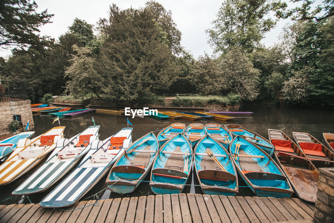 Multi colored boats moored by swimming pool against lake in oxford, england