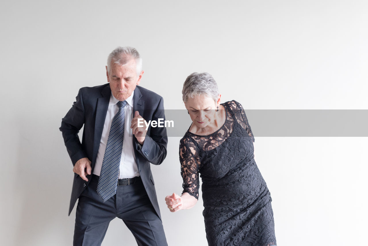 Senior couple dancing against white background